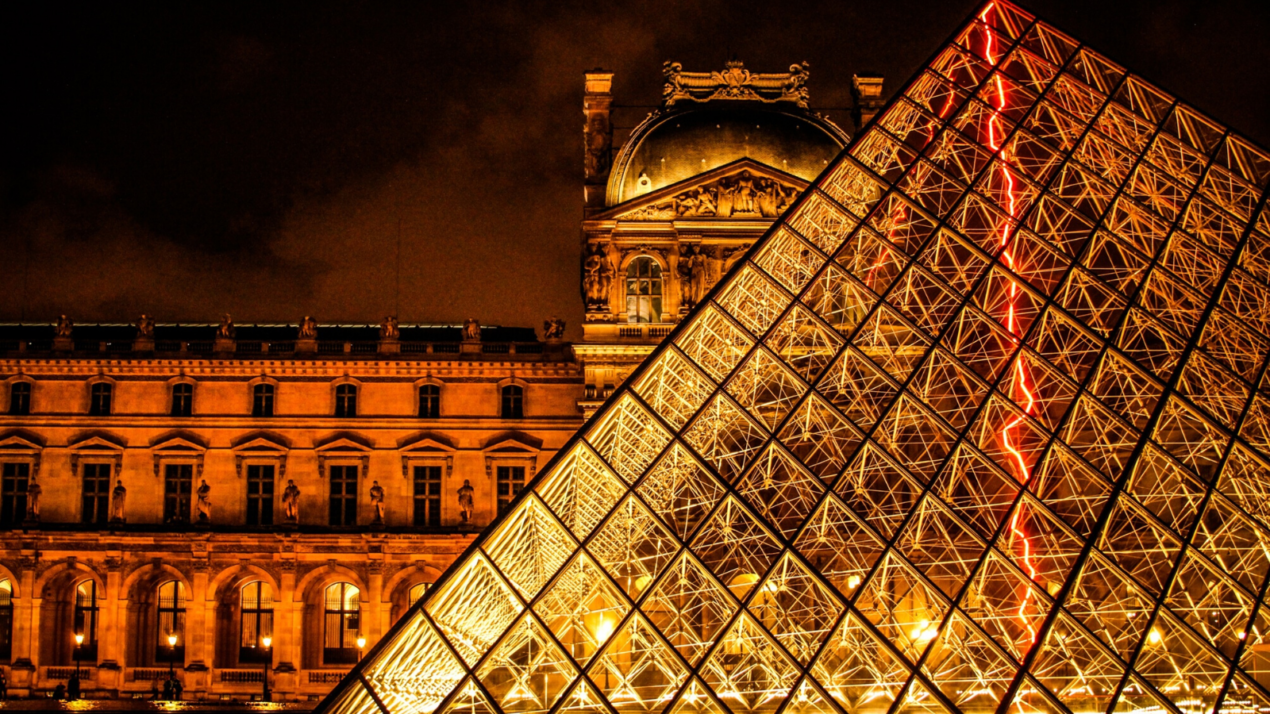 The Louvre Pyramid illuminated at night in front of the Louvre museum