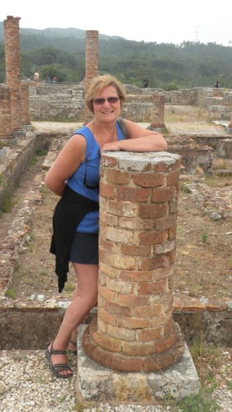 The author Carol Cram next to a pillar in the Roman ruins of Coninbriga in Portugal