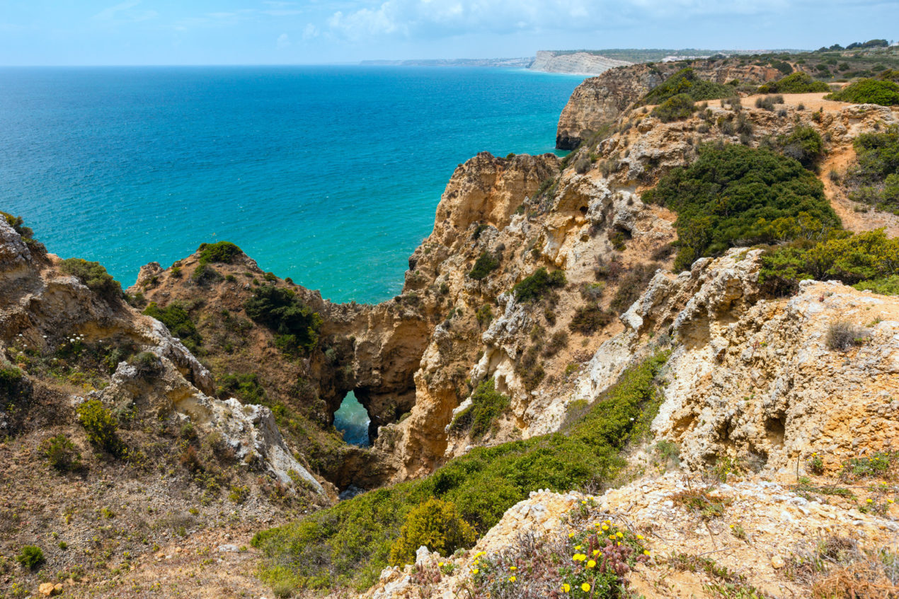 Breathtaking rocky coastline of the Algarve with turquoise waters and dramatic cliffs, a scenic detour for travelers extending their Andalusia itinerary to Southern Portugal.