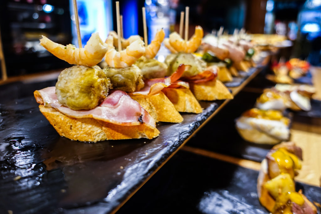 A selection of pintxos - small pieces of bread piled high with shrimps, artichokes and ham. Enjoying pintxos is a highlight of visiting Spain.
