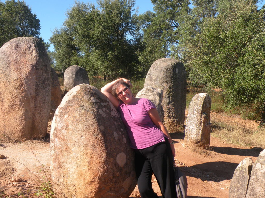 The author leaning against an ancient dolmen at Cromeleque dos Almendres, a megalithic site near Evora in Portugal.