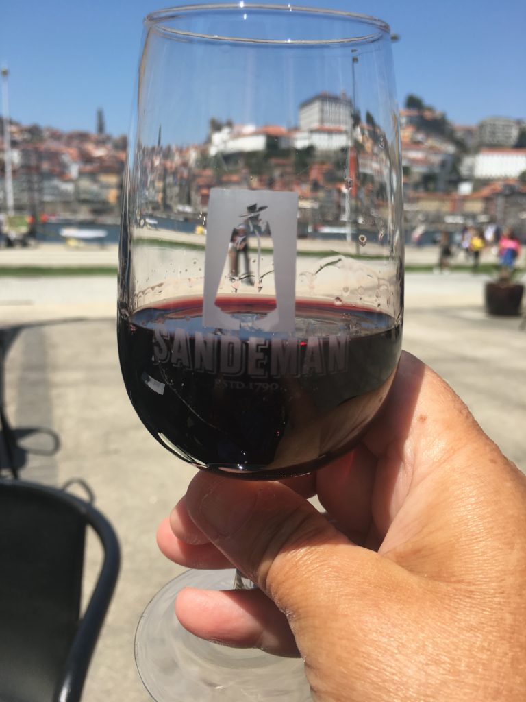 A glass of port with the town of Porto in the background