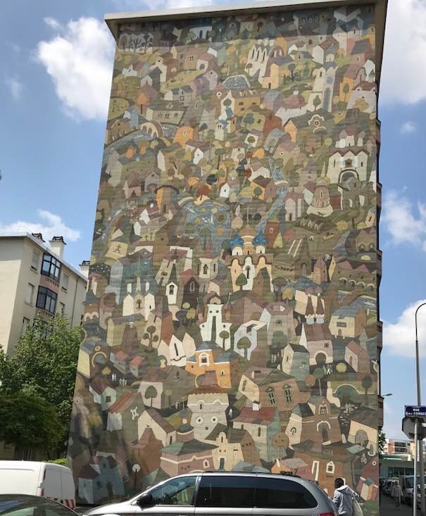 Large mural on the side of a buliding of a jumble of houses in a village in Lyon