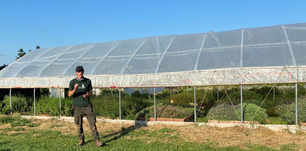 Farmer Petrie stands in front of a greenhouse at the Inn at Bay Fortune prior to the FireWorks Feast