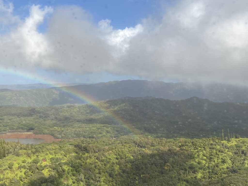 A rainbown arcing across green mountains on Kauai as seen from a helicopter flight over Kauai--a vacation highlight.