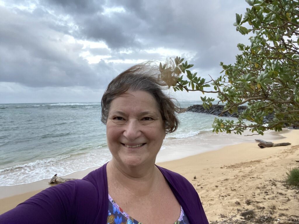 Photo of the author Carol Cram traveling solo on the beach steps for Kauai Beach Villas