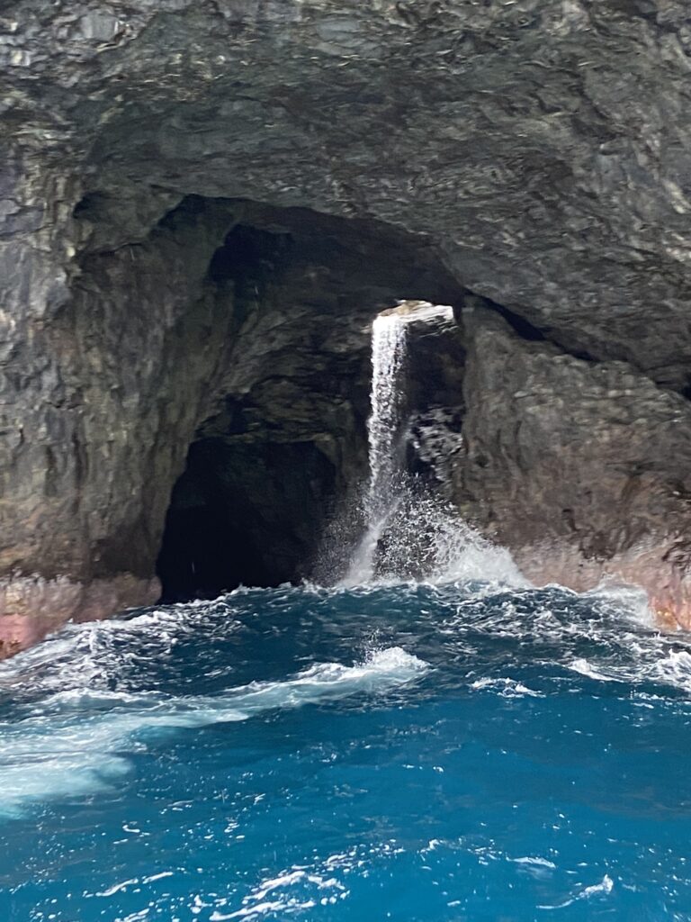 Waterfall plunging into a sea cave along the Napali Coast in Kauai; a boat trip of the area is a highlight of a Kauai vacation.