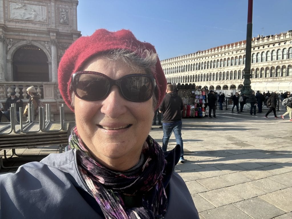 Carol Craqm wearing a red tam standing in St. Mark's square during a visit to Venice in November.