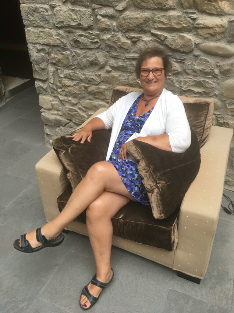 Carol Cram sitting in a comfortable chair in the courtyard of a charming hotel in Spain