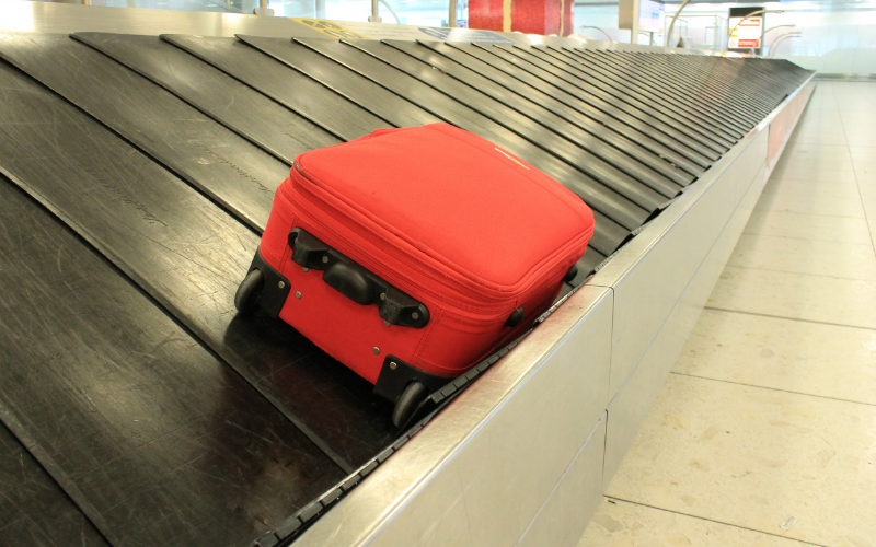 Red suitcase on a luggage carousel; get equipped for travel means choosing a good suitacase.