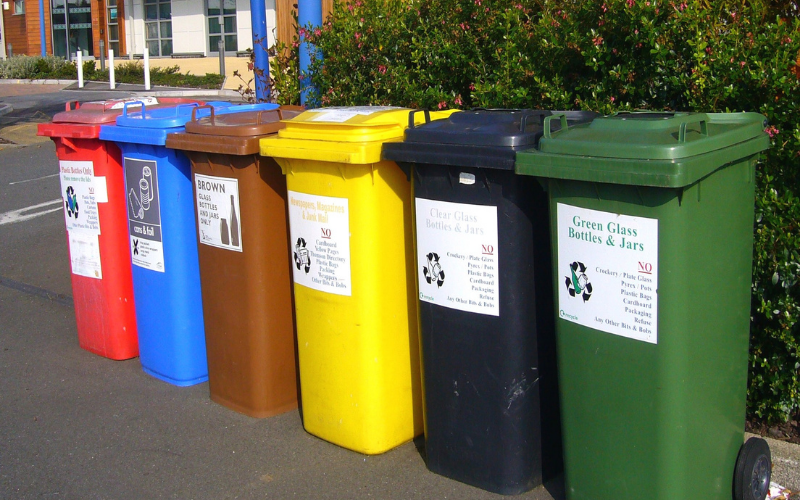 Row of brightly colored recyling containers; travel green by using them.