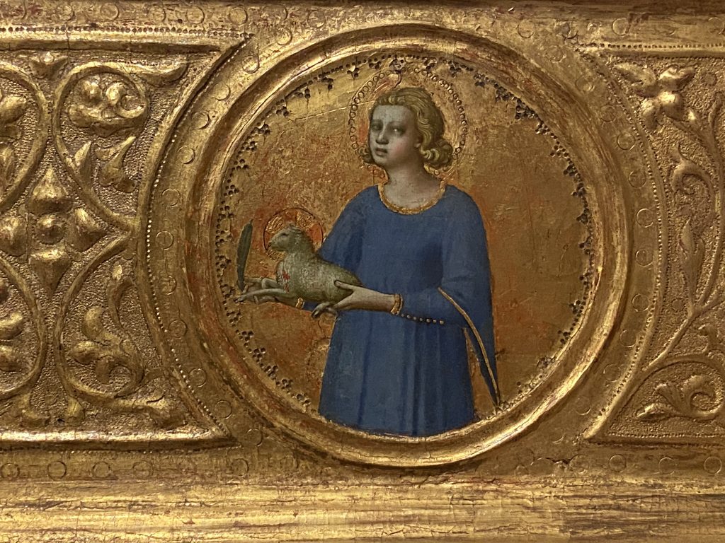 Medieval gold panel that includes a portrait of a female saint wearing a simple blue gown and created by Fra Angelico included in the Medieval collection at the Courtauld Gallery in London.