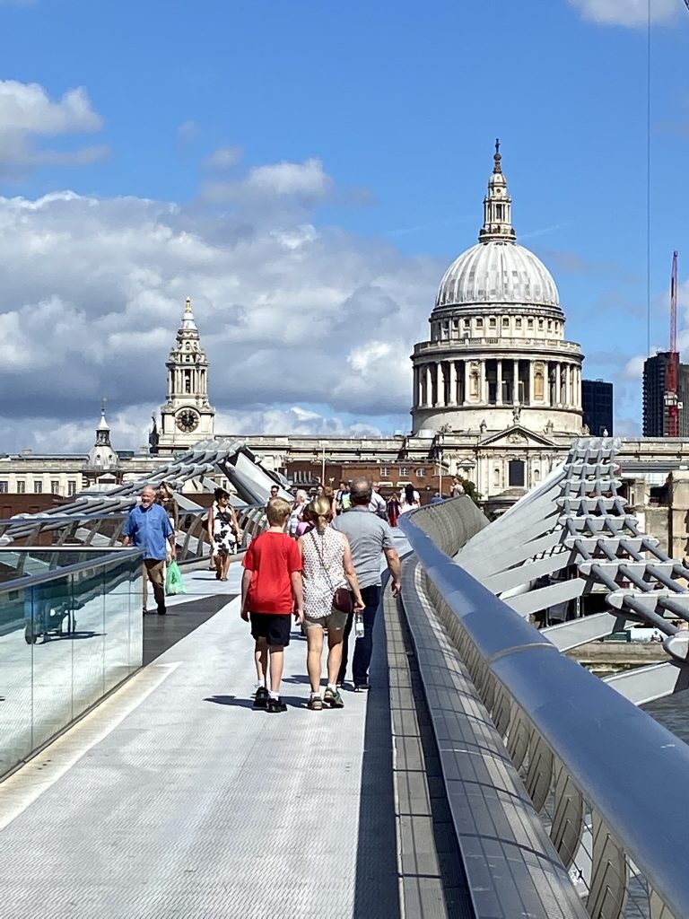walking across the pedestrian bridge over the Thames in London with Saint Paul's Cathedral in the distance