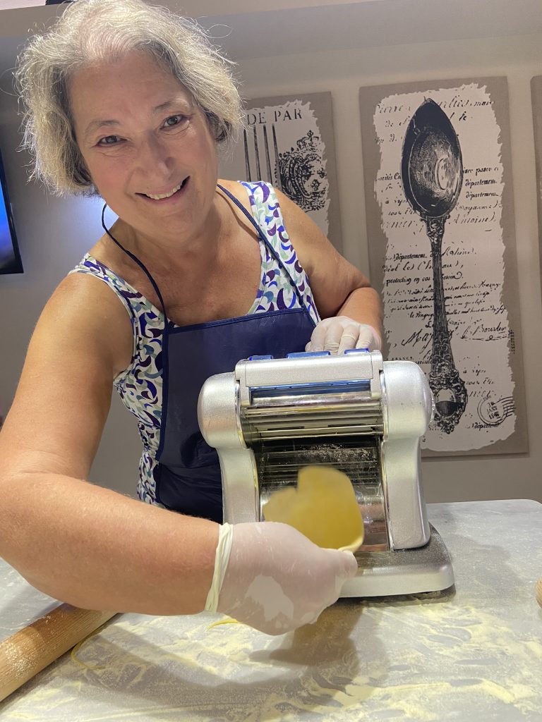 Carol Cram passing pasta dough through a pasta maker at the InRome Cooking school