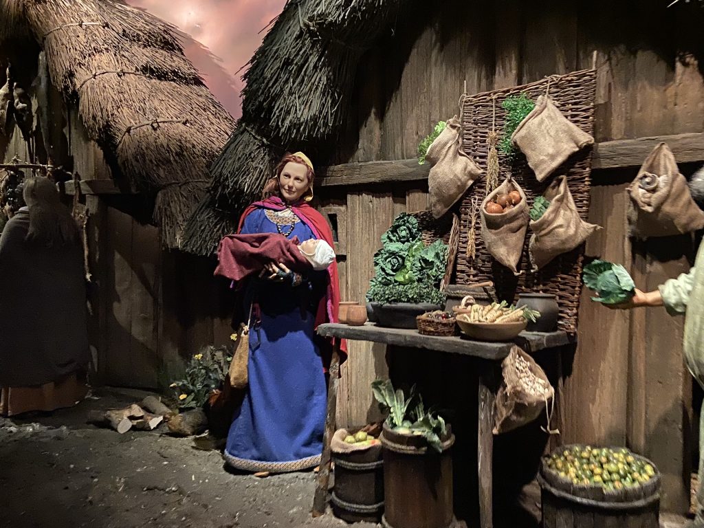 Costomed Viking woman with child next to a vegetable stall at the Jorvik Viking Center in York in Yorkshire
