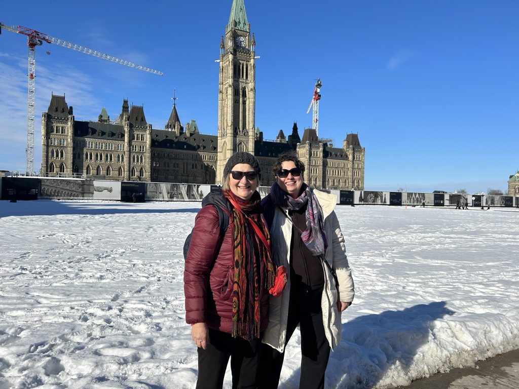 Carol Cram & Julia Simpson in front of the Parliament buildings in Ottawa, Canada