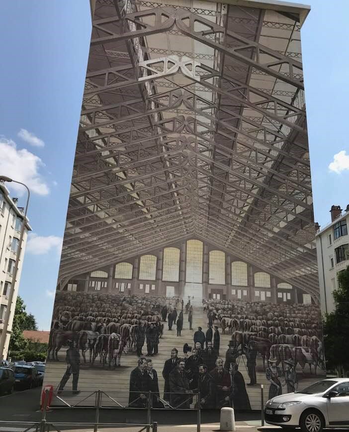 Mural showing the interior of a large dairy barn on the side of a building in Lyon