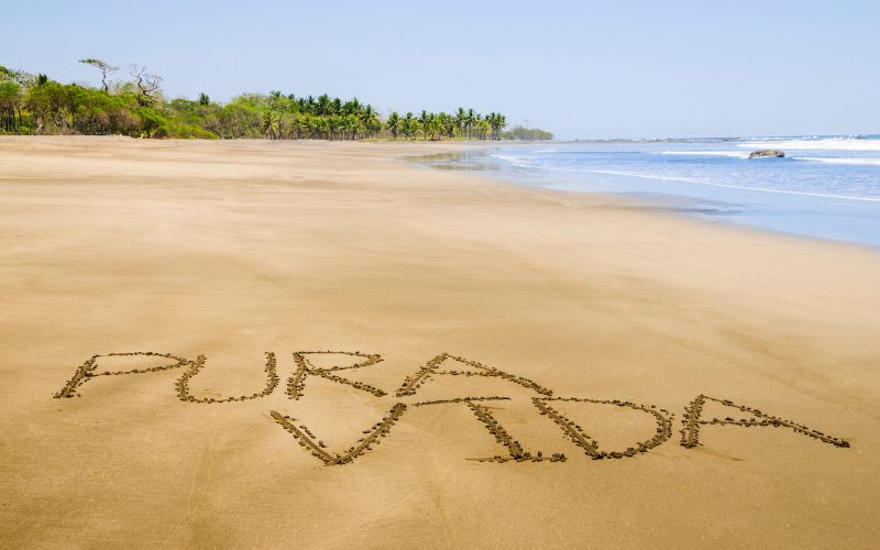 Pura Vida etched into the sand on a pristine beach in Costa Rica
