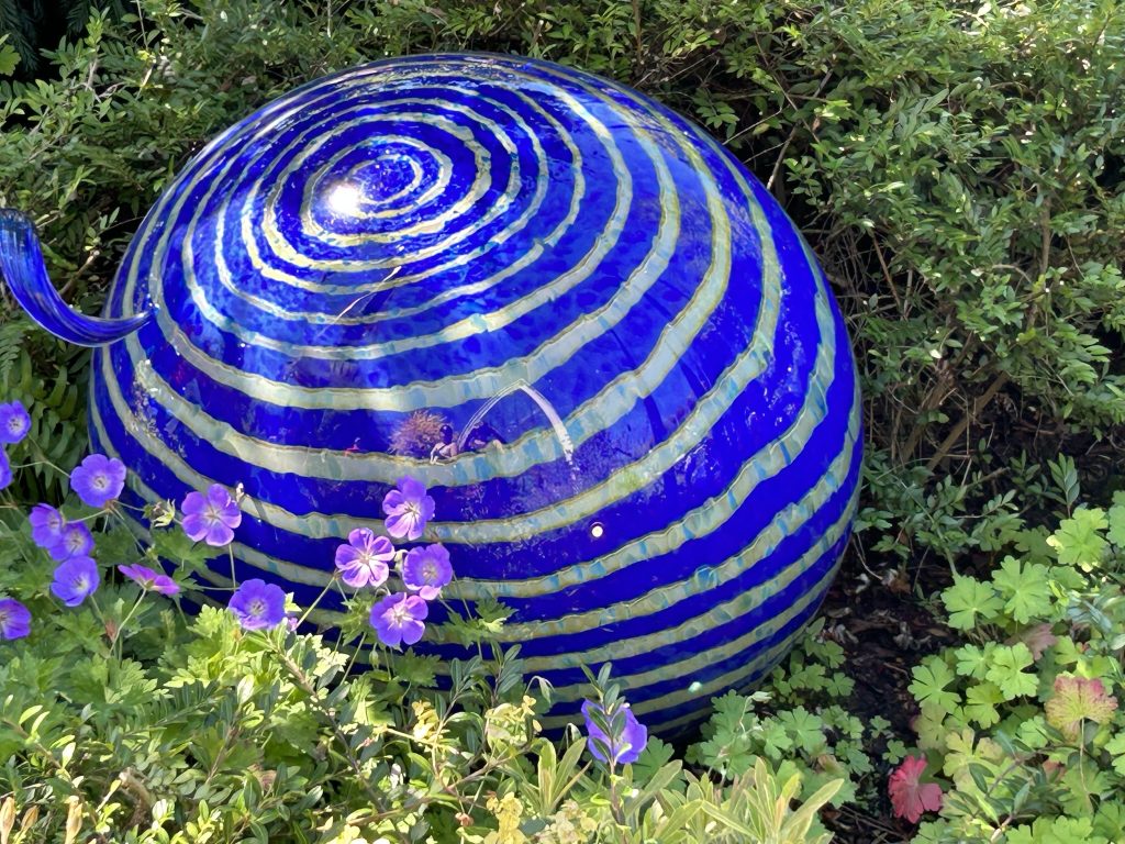 Large gold and blue striped glass orb in the garden at Chihuly Garden and Glass in Seattle