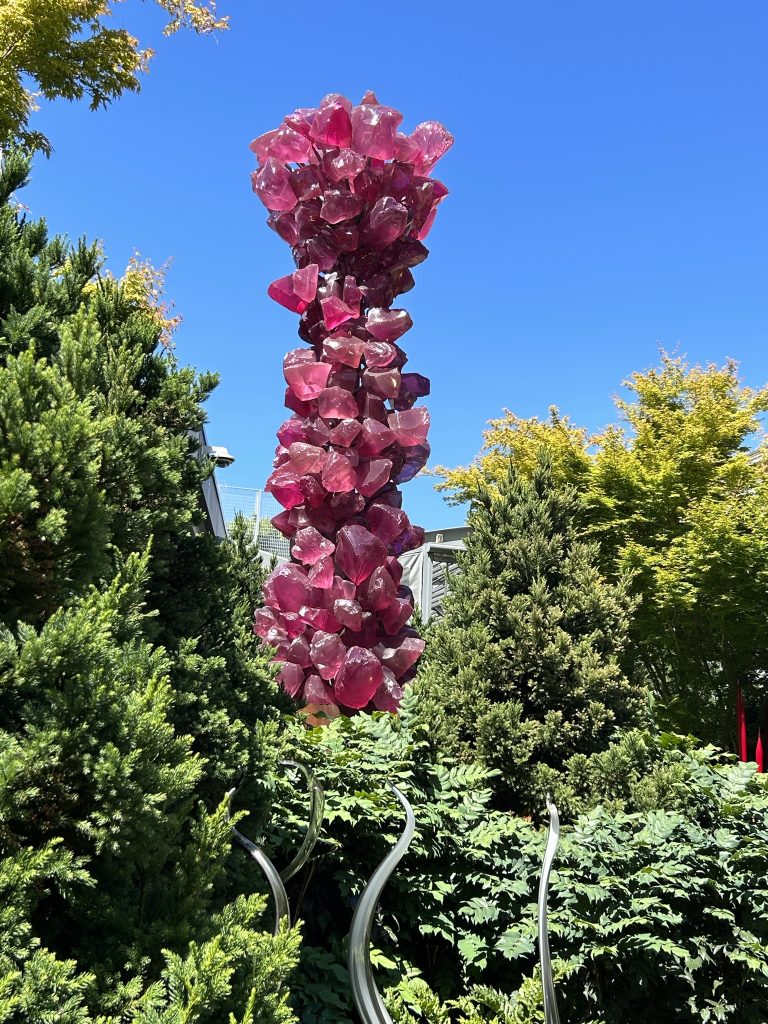 Large vertical sculpture consisting of magenta glass boulders in the garden at Chihuly Garden and Glass in Seattle