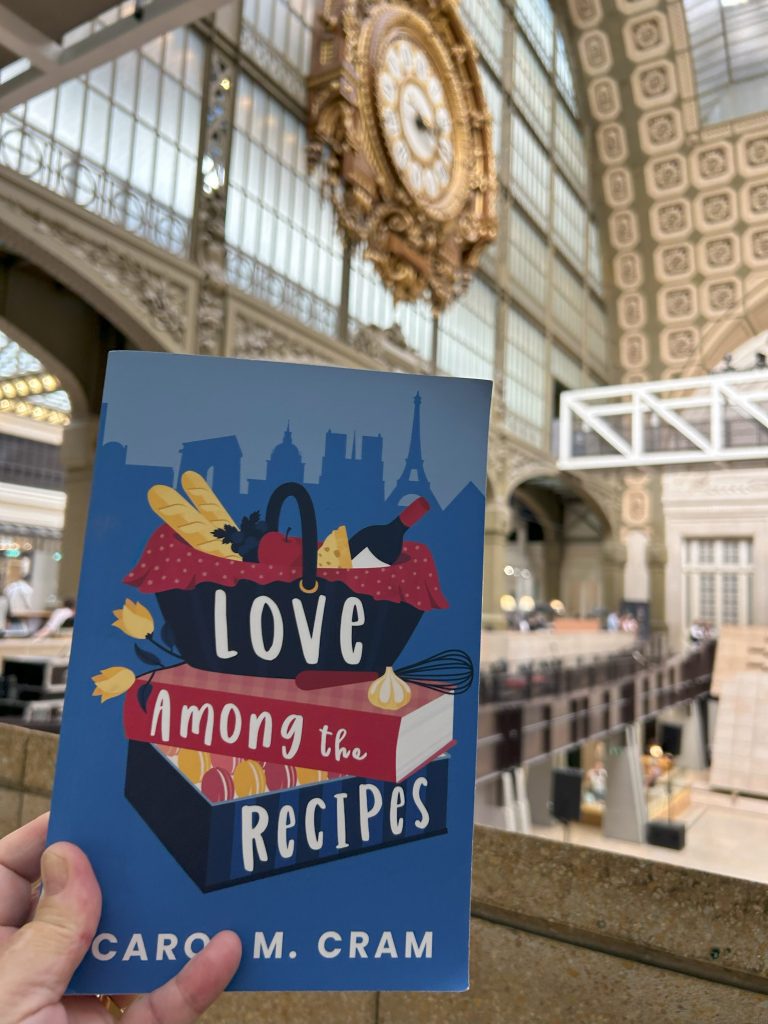 Love Among the Recipes by Carol M. Cram in front of the clock at the Musees d'Orsay in Paris