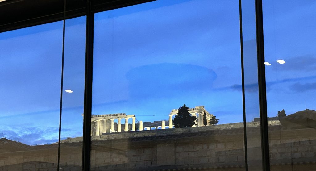 Floodlit view of the Acropolis as seen through a large window on the top flow of the Acropolis Museum.