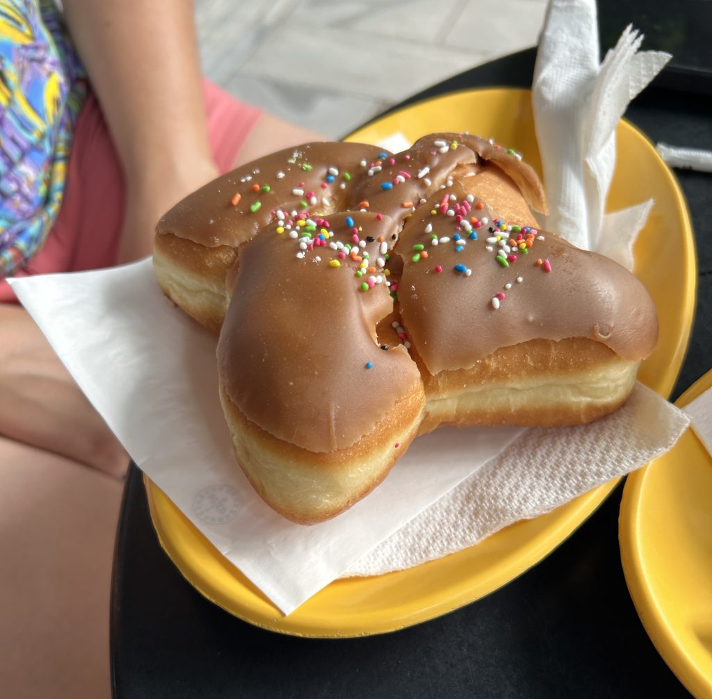 Picture of a very large and dry donut with caramel icing flaking off as an example of what not to order at the touristy cafes near the Acropolis in Athens.