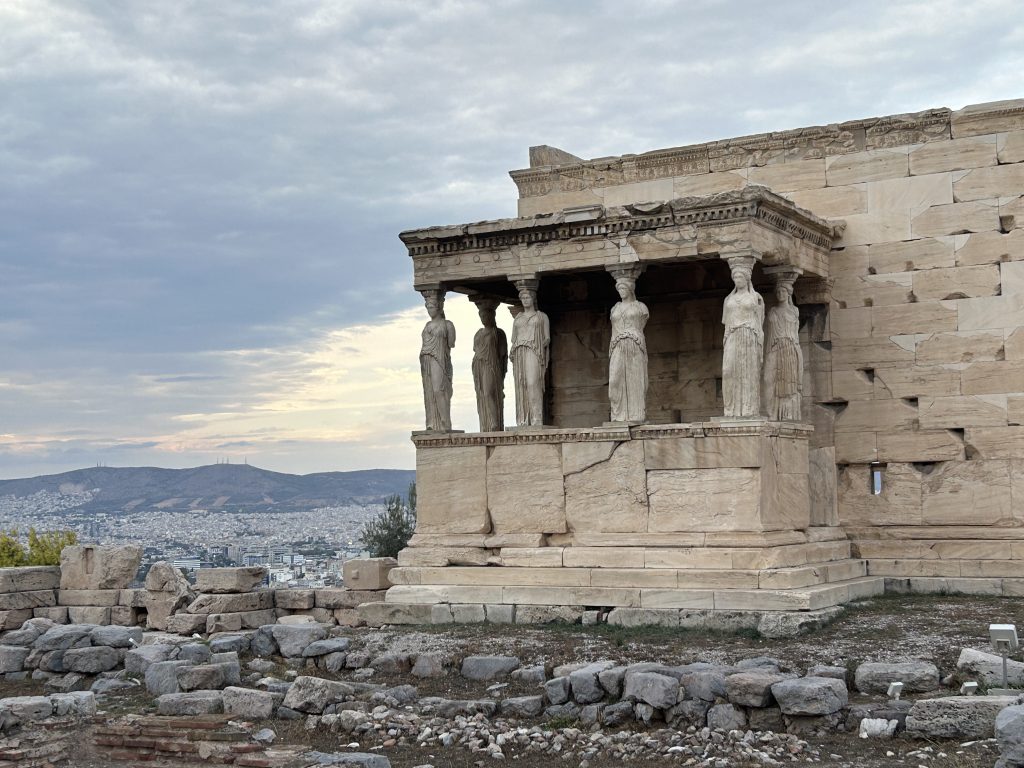 The Temple of Erechtheion on the Acropolis with a view of the Athens skyline beyond. This temple is a highlight of the Acropolis because the columns are actually statues of women in Greek robes.