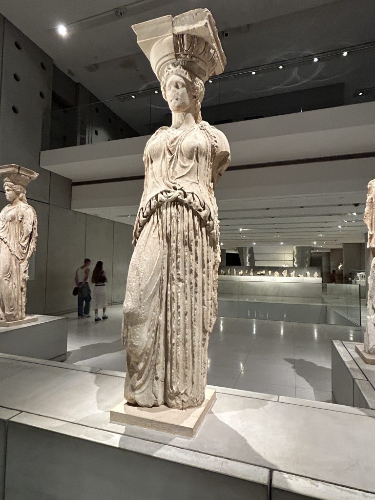 View of one of the female statues wearing Greek robes with pediments on top of it head. This is one of the original columns used to hold up the Erechtheion Temple on the Acropolis, and is very classically Greek and beautiful. The column is displayed in the Acropolis Museum--a must-see museum in Athens.