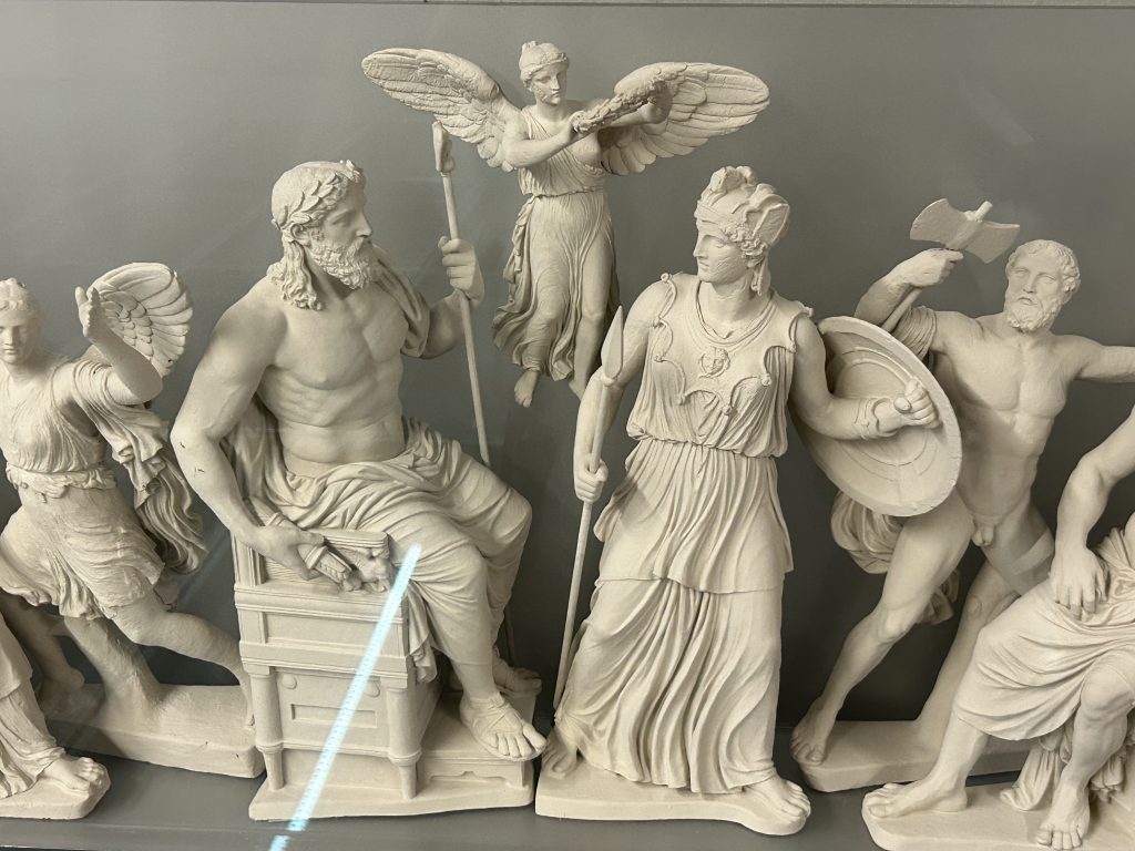 Reconstruction of a portion of the frieze that once adorned the Parthenon at the Acropolis exhibited in the Acropolis Museum in Athens. This portion shows marble statues of two Greek Gods and other figures and is very white and beautiful.