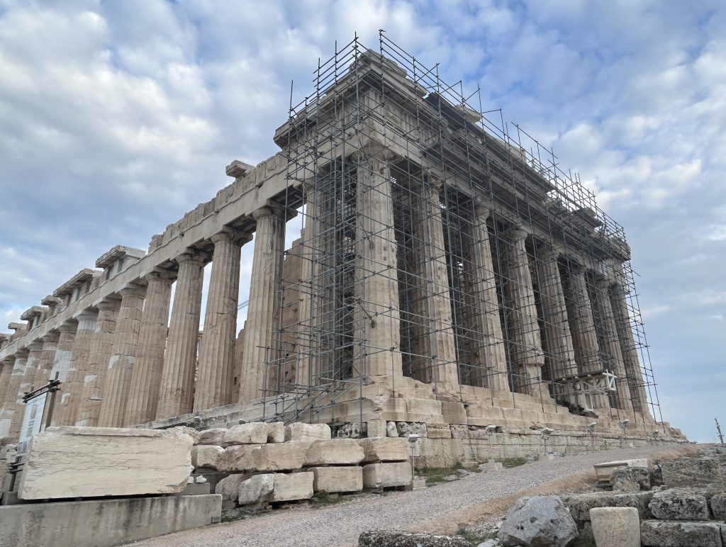 Front view of the Parthenon in Athens which is covered in scaffolding. The columns along the left side do not have scaffolding and are Doric columns and very beautiful.