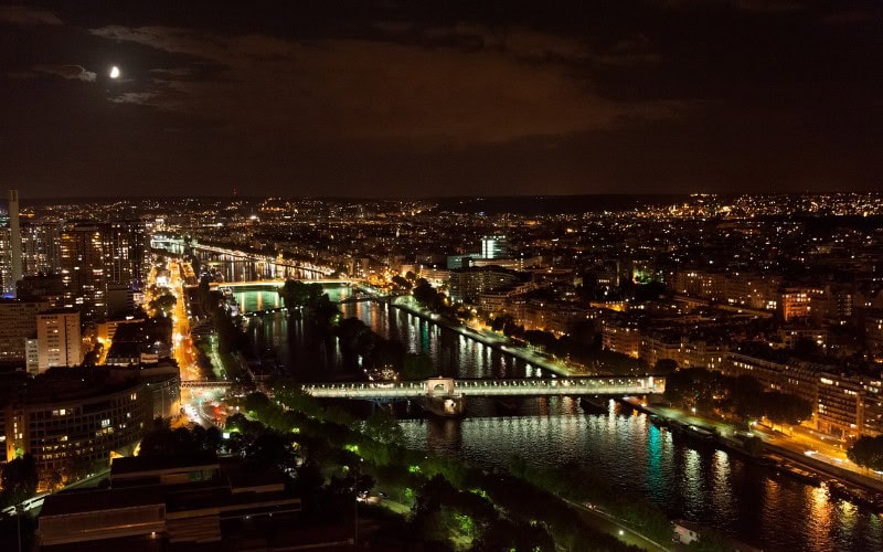 A breathtaking view of the Eiffel Tower illuminated against the night sky, with reflections in the nearby Seine River.