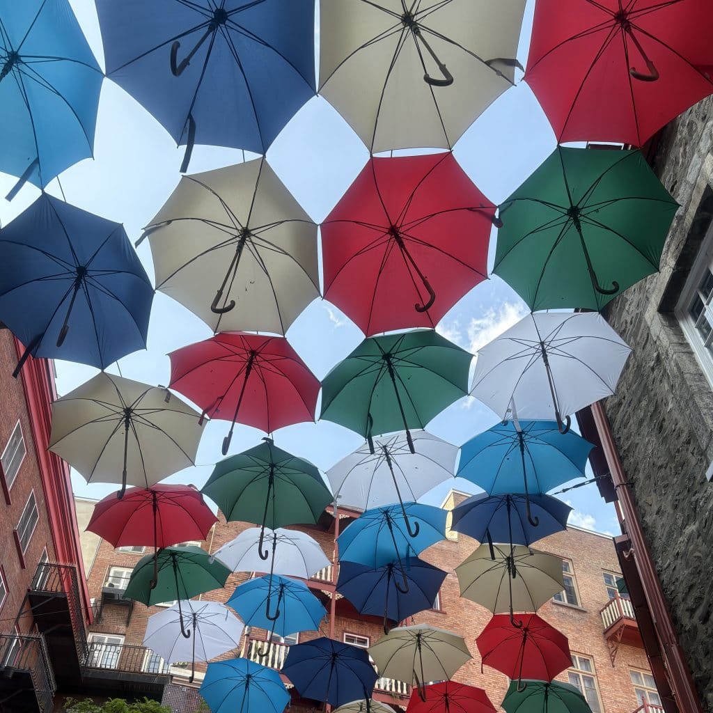 Colorful umbrellas suspended between two buildings in Old Quebec City
