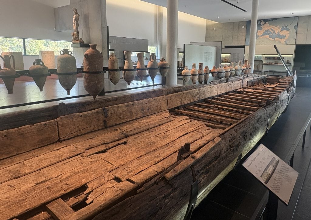 View of the 30 meter Roiman barge recovered from the Rhone and on display at the Musée Départemental Arles Antique (Museum of Ancient Arles and Provence). To the left of the barge is a long row of intact amphorae also recovered from the Rhone.