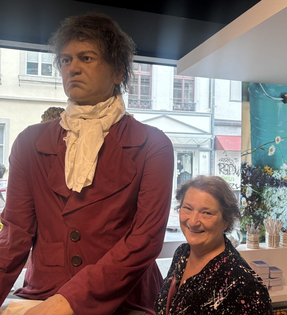 Carol Cram next to a larger than lifesize seated statue of Ludwig Van Beethoven in the gift shop at the Beethoven Museum in Bonn, Germany