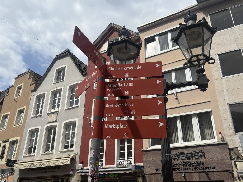 Selection of Red directional signs in a pedestrian area of Bonn, Germany.  One sign points to Beethoven-=Haus