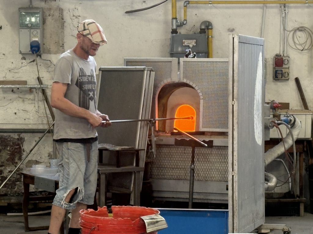 Man doing a glass blowing demonstration at a furnace in Murano