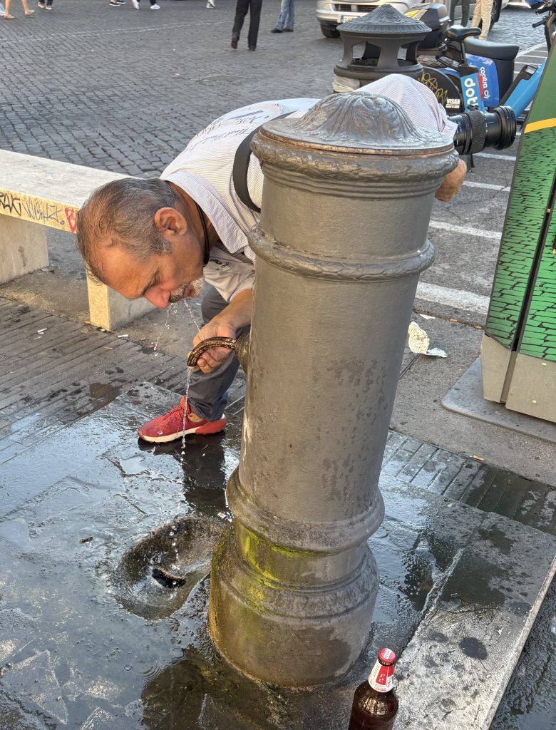 Giulio D'Ercole who runs Rome Photo Fun tours taking a drink from a Nasoni in Rome (a water fountain)
