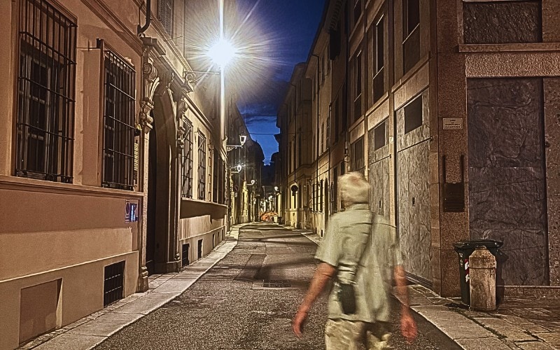 Deserted street in Piacenza at night with the figure of a man walking in the foreground