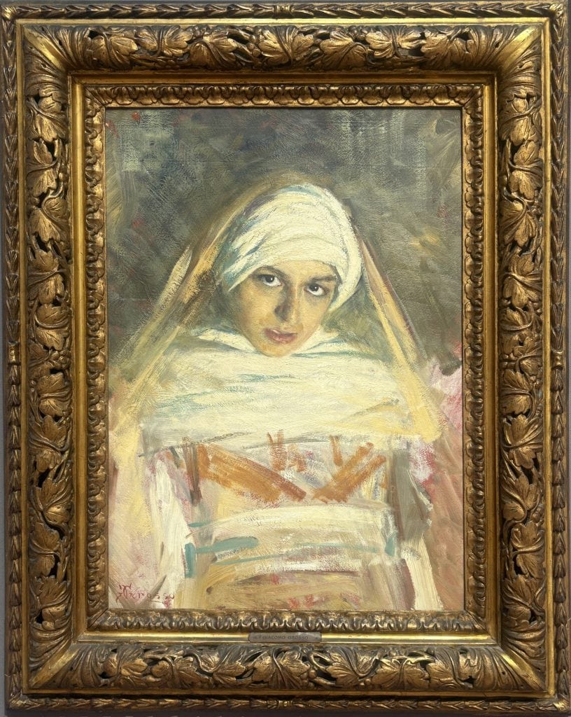 Painting called Occhi Nero of a girl in a turban staring out at the viewer and painted in an early 20th century impressionist style by Amaedeo Bocchi in the Galleria d’arte moderna Ricci Oddi in Piacenza
