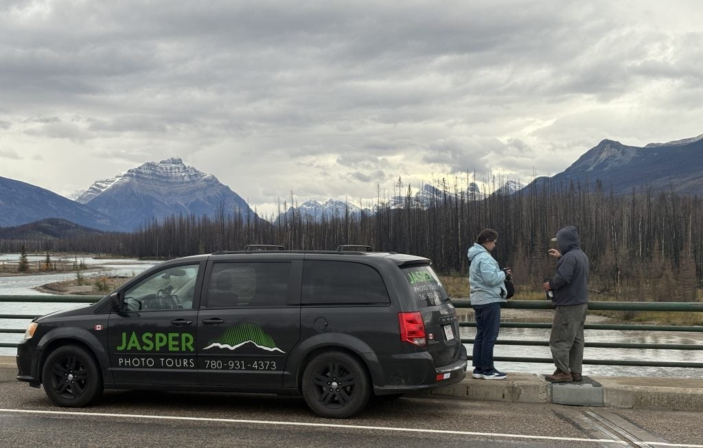 car with logo of Jasper Photo Tours in front of a river and mountain
