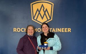 Carol Cram, the author of Artsy Traveler with her daughter Julia Simpson in front of the Rocky Mountaineer sign i n Jasper, Alberta