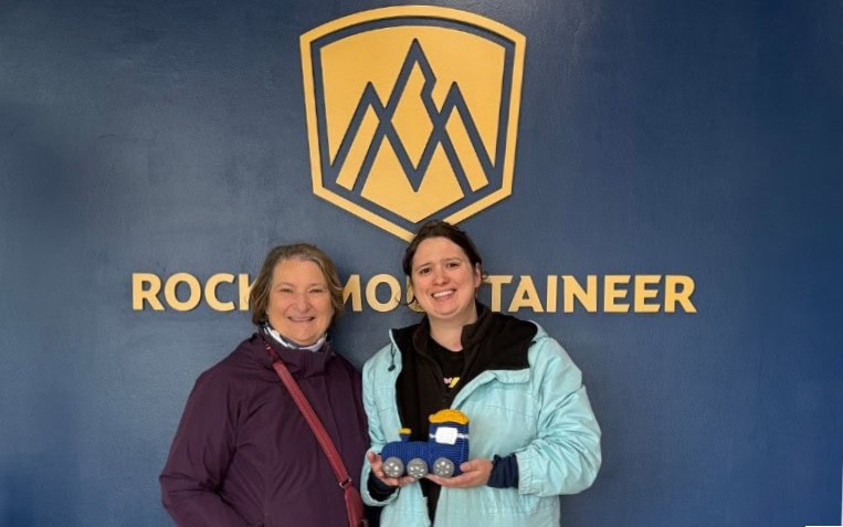 Carol Cram, the author of Artsy Traveler with her daughter Julia Simpson in front of the Rocky Mountaineer sign i n Jasper, Alberta