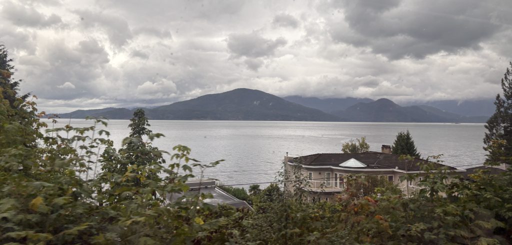 View of Bowen Island across Howe Sound from the Rocky Mountaineer train on its journey from Vancouver to Whistler on a misty, cloudy day. 
