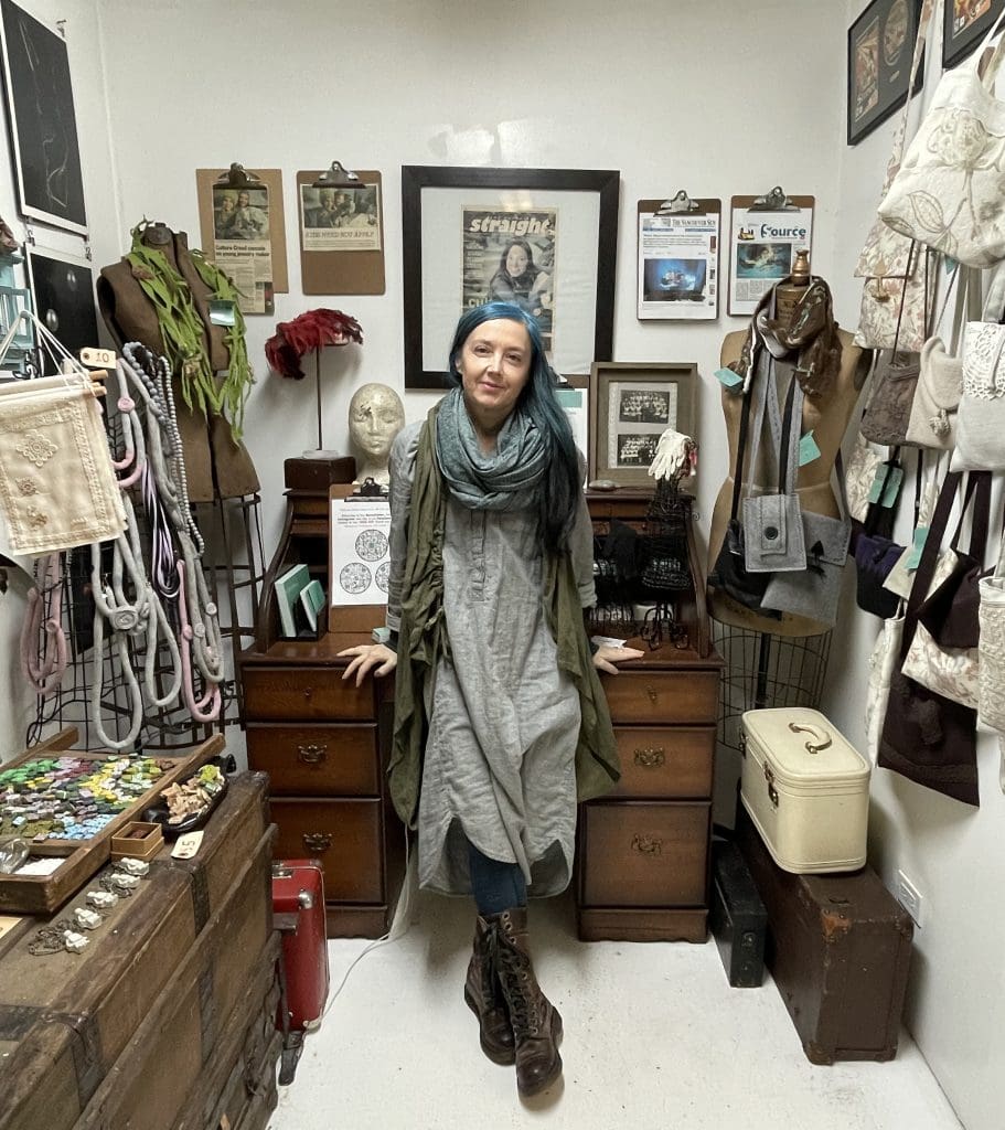 Beaty Kazy, owner of Soigne, standing among her crafts including jewelry, purses and antique furniture
