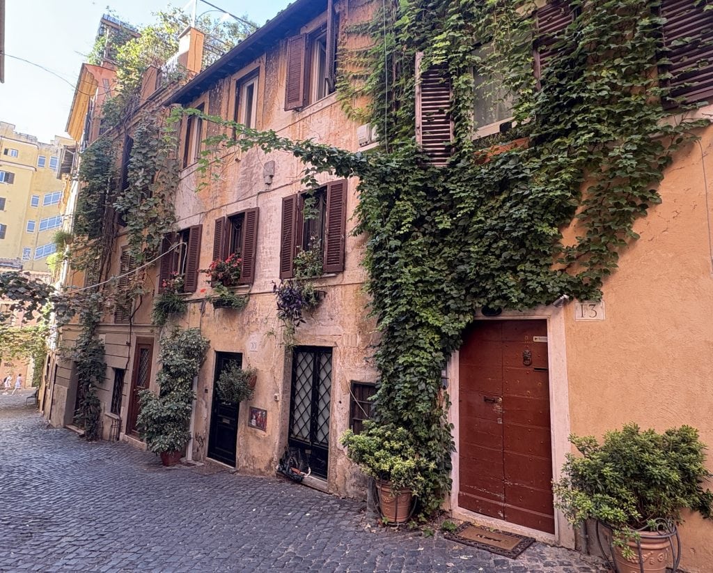 Tranquil street scene in Rome showing a pink house covering in ivy