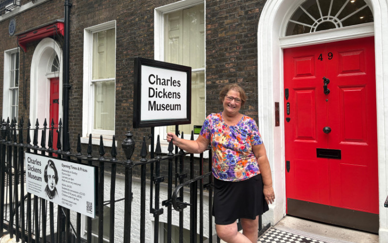 Carol Cram in front of the red door leading to the Charles Dickens Museum in London
