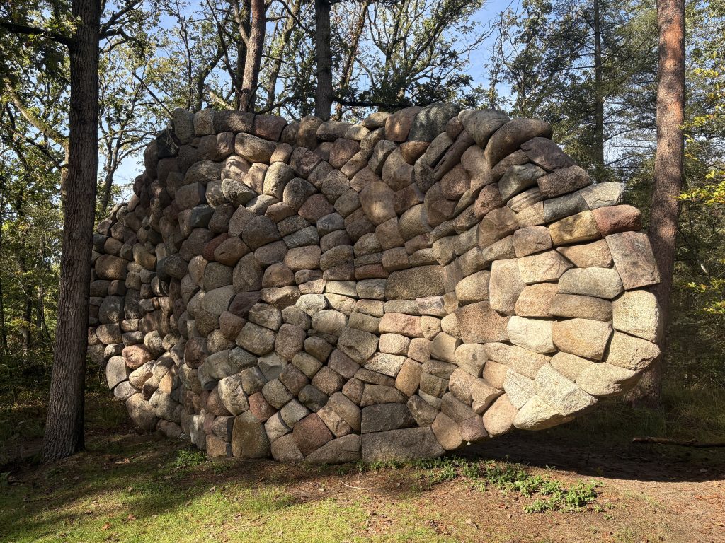 Chris Booth's stacked stone sculpture Echo van de Veluwe curving like a wave through the woods