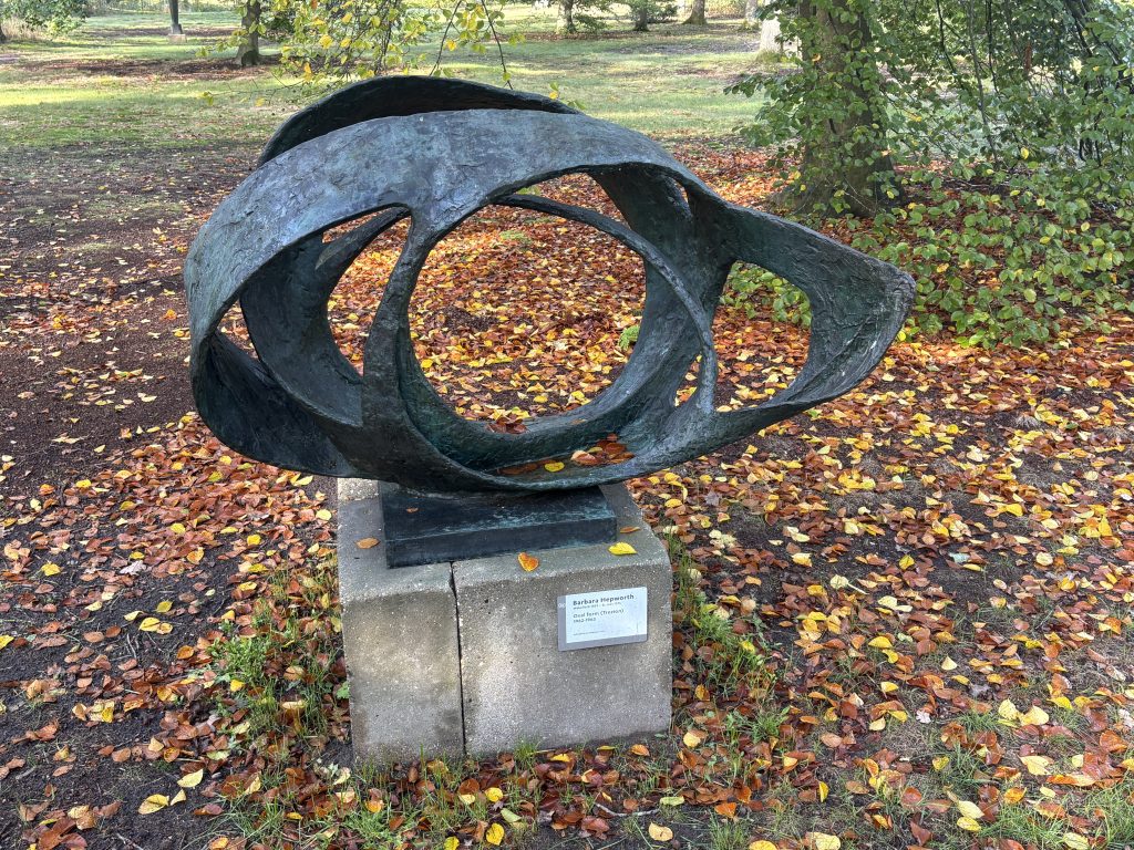 Barbara Hepworth's bronze Oval Form (Trezion) resting on a carpet of autumn leaves in the Kröller-Müller sculpture garden