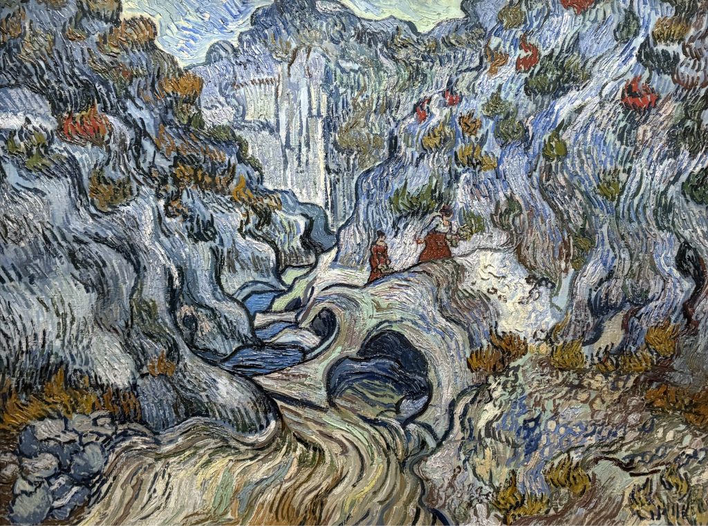 Van Gogh painting of a rocky ravine rendered in swirling blue and grey strokes with two small figures on a path